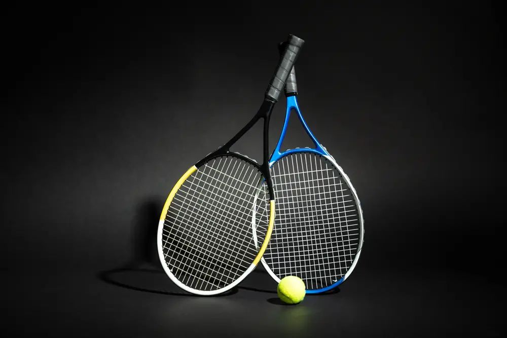 Close-up Of Tennis Racket With Green Ball On Back Background