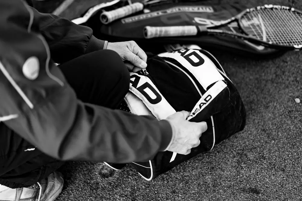 Tennis player fastens tennis bag.