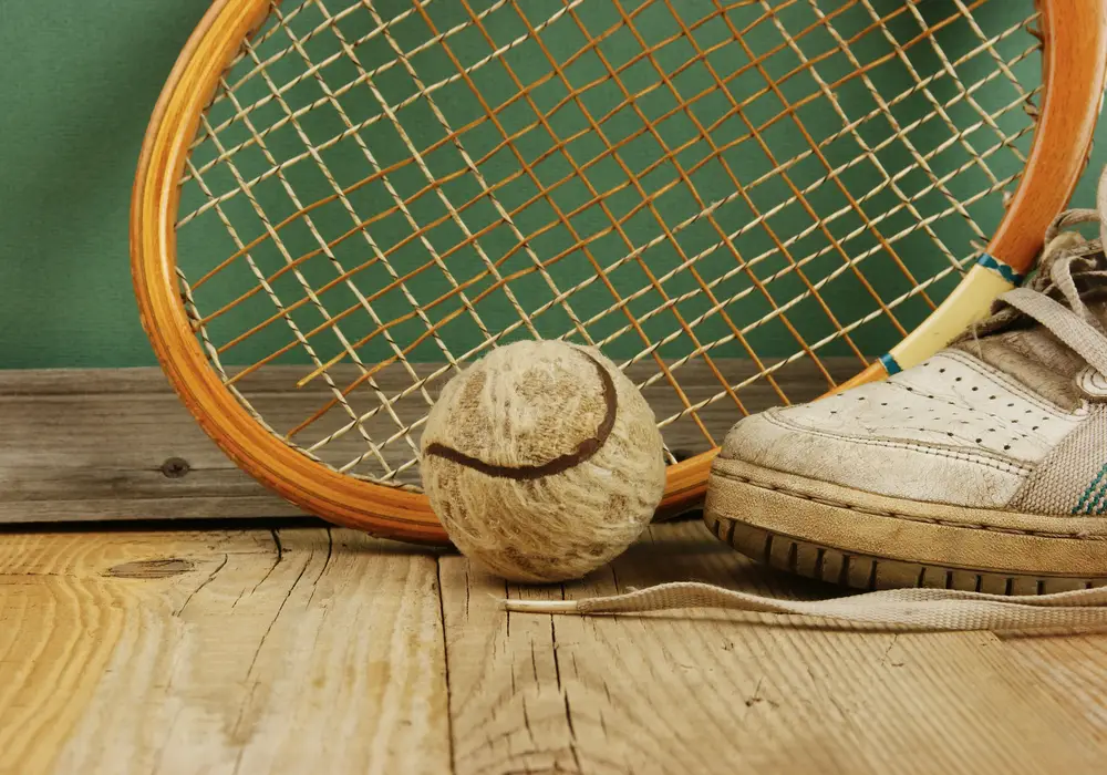 old tennis ball and racket with sneakers