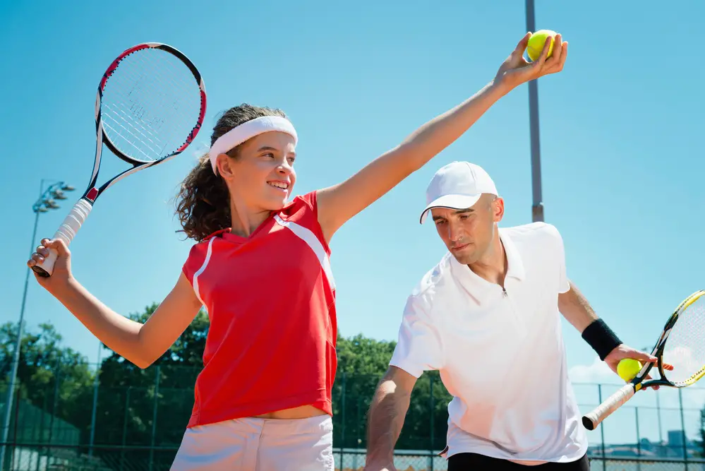 Tennis instructor polishing serving power posture with student