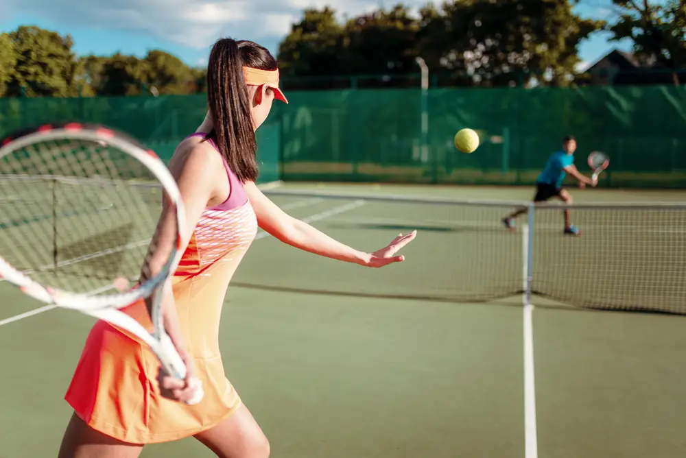 Couple playing tennis on outdoor court.