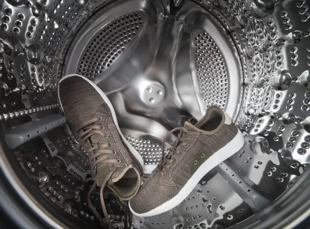 Sports sneakers in metal drum of washing machine close-up.